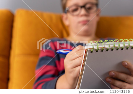 boy concentrating on drawing in his notebook in a moment of creative inspiration boy concentrating on drawing in his notebook in a moment of creative inspiration 113043156