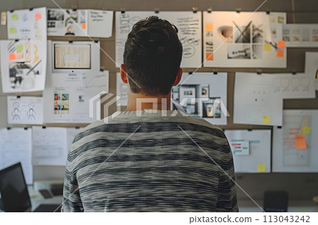 Man Standing in Front of Wall Covered With Papers Man Standing in Front of Wall Covered With Papers 113043242