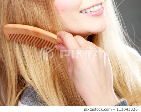Closeup woman combing her hair with comb 113043326