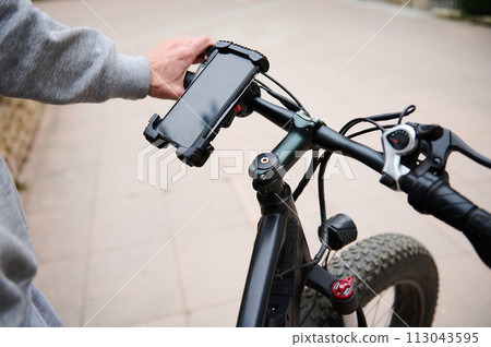 Cyclist sets up adjustments on mockup smartphone, renting electric bike using rental app. Bike sharing city service. 113043595