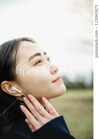 Profile of a woman listening to music with earphones 113043871