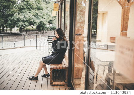 高中女孩坐在長椅上喝飲料 高中女孩坐在長椅上喝飲料 113043924