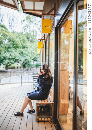 高中女孩坐在長椅上喝飲料 113043927