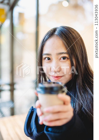 A high school girl sitting on a bench and drinking A high school girl sitting on a bench and drinking 113043936