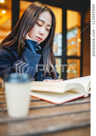 女高中生在咖啡館外的座位一邊喝飲料一邊看書 女高中生在咖啡館外的座位一邊喝飲料一邊看書 113043989