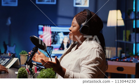 Internet show host speaking with guest during live broadcast for social media website, listening to her opinion. Internet influencer using professional gear to record podcast Internet show host speaking with guest during live broadcast for social media website, listening to her opinion. Internet influencer using professional gear to record podcast 113044230