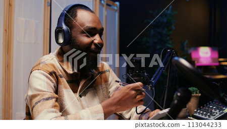 Zoom in on african american man on podcast discussing with guest during marathon stream for humanitarian cause. Host chatting with celebrity, gathering donations from audience during internet show Zoom in on african american man on podcast discussing with guest during marathon stream for humanitarian cause. Host chatting with celebrity, gathering donations from audience during internet show 113044233