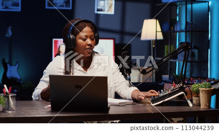 Woman arriving in studio, broadcasting live on streaming platform using professional tools producing high quality audio. Influencer putting headphones on, creating engaging social media content 113044239