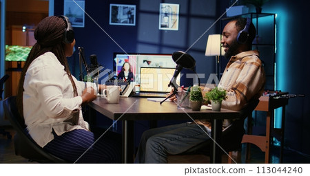 Show host and guest arriving in studio to record podcast with professional equipment. Woman and man fist bumping coming in broadcasting space using quality audio devices for flawless sound 113044240