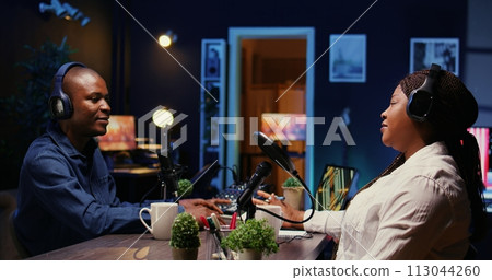 Woman laughing during comedy focused podcast, entertained by funny internet show host. Talking show interviewer broadcasting live from studio, telling jokes to audience watching at home Woman laughing during comedy focused podcast, entertained by funny internet show host. Talking show interviewer broadcasting live from studio, telling jokes to audience watching at home 113044260