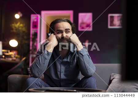 Depressed man looking saddened at TV display while playing videogames, receiving game over screen on gaming console. Gamer putting face in hands, upset after being defeated by enemy players Depressed man looking saddened at TV display while playing videogames, receiving game over screen on gaming console. Gamer putting face in hands, upset after being defeated by enemy players 113044449