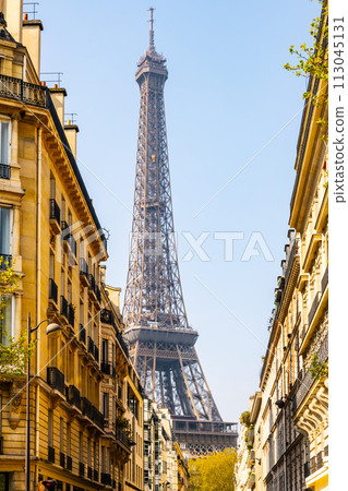 The Eiffel Tower stands tall against a clear blue sky, framed by the traditional buildings of a Parisian street. Paris, France 113045131