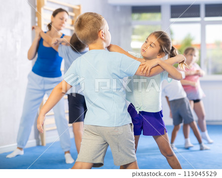 Boys and girls in gym perform basic elements of krav maga self-defense system. 113045529