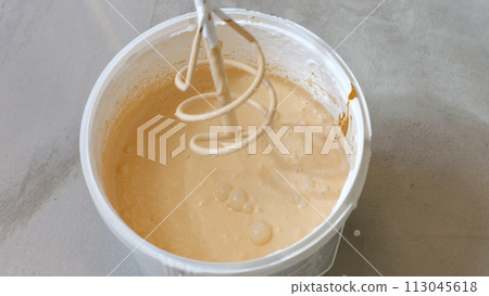 Preparation of paint for painting walls. A mixer and a bucket of paint. 113045618