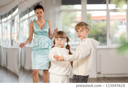 Tween girl and boy practicing waltz in dance hall with female mentor Tween girl and boy practicing waltz in dance hall with female mentor 113045628
