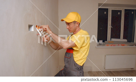 Electrician puts socket. Electrician makes the job of electricity. 113045696