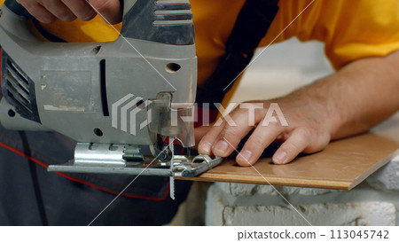 Builder sawing jigsaw laminate. Worker cuts wood. 113045742