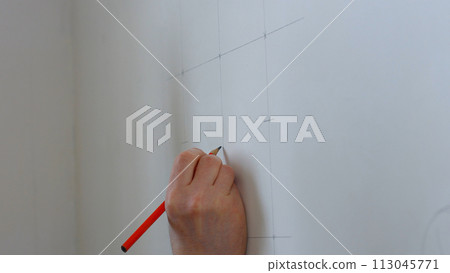 Builder draws marking on the wall. Worker making measurements. 113045771
