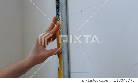 A specialist draws markings on the wall. Lines are drawn for future fastening. 113045773