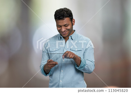 Smiling young man using transparent digital tablet. Abstract bokeh background. 113045820
