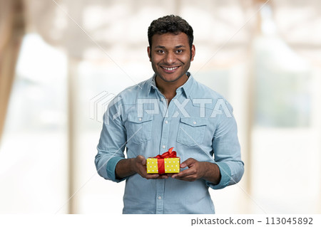 Handsome smiling man holding gift box and looking at camera. Birthday present for her. 113045892