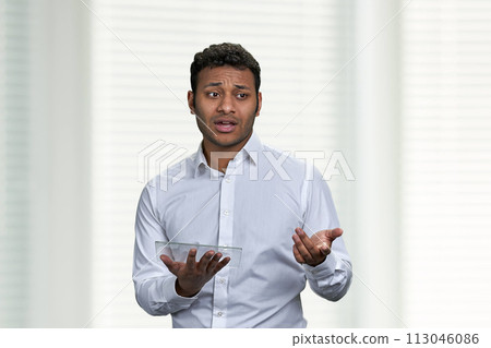Indian business coach using futuristic digital tablet. Young dark-skinned business man giving a presentation on white background. 113046086