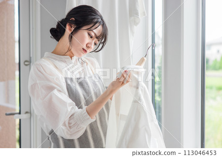 A housewife who is worried about stains on the collar of her laundry shirt (yellowing, bleach, detergent, sweat stains, dirt) 113046453