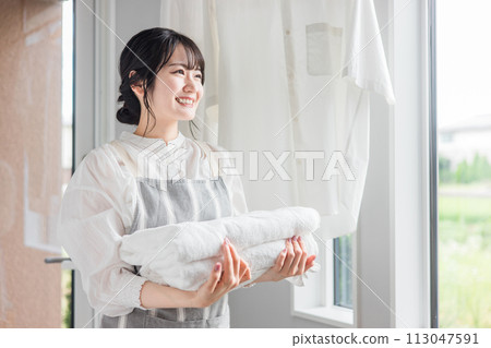 洗衣房/更衣室裡拿著洗過的浴巾的家庭主婦 洗衣房/更衣室裡拿著洗過的浴巾的家庭主婦 113047591