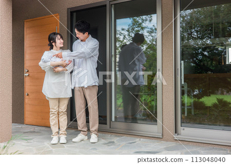 Owner couple and baby standing in front of the entrance of a newly built home/detached house/detached house/couple/family Owner couple and baby standing in front of the entrance of a newly built home/detached house/detached house/couple/family 113048040
