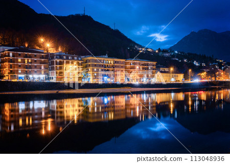 Night view of Lecco. Reflection of city lighting in the water. Night view of Lecco. Reflection of city lighting in the water. 113048936
