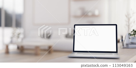 A close-up image of a laptop computer mockup on a table in a luxurious contemporary living room. 113049163