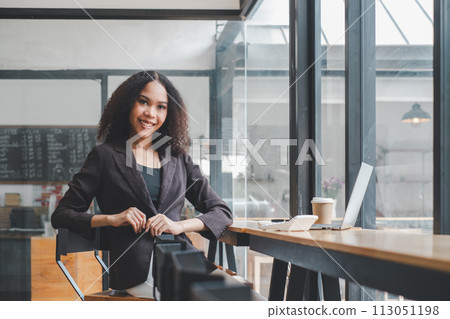 Confident young businesswoman at a cafe with laptop and smartphone, ready for a productive workday. 113051198