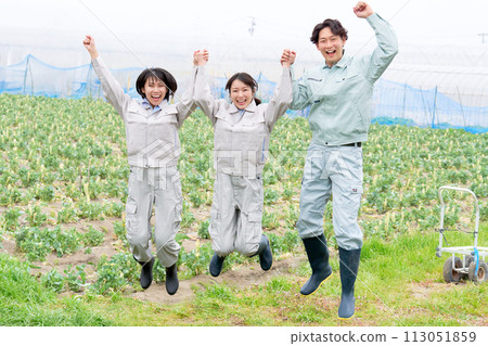 Young people in agricultural uniforms holding hands and jumping 113051859