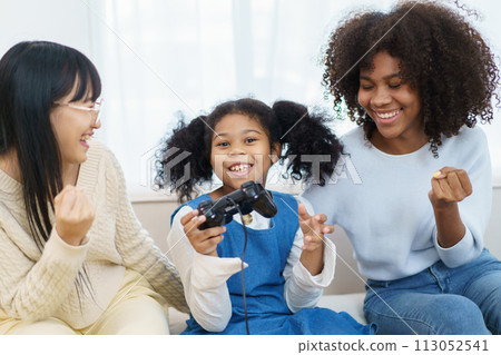 Concept of diversity in ethnic people spending a time together in a weekend. A diverse group and generation people relaxing and playing a video game together in living room. 113052541