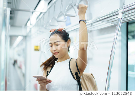 Happy Asian female tourist traveling in across the country by railway transportation system. Woman holding on the handle grip while traveling in the train. 113052848