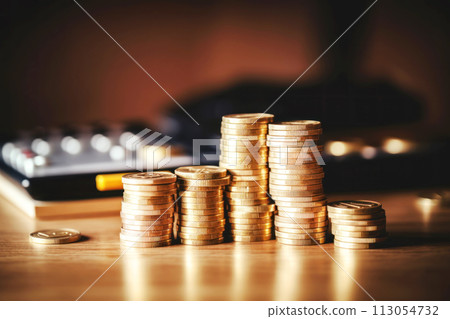 Stack of coins and calculator on wooden desk 113054732
