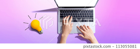 Person using a laptop computer and a light bulb Person using a laptop computer and a light bulb 113055081