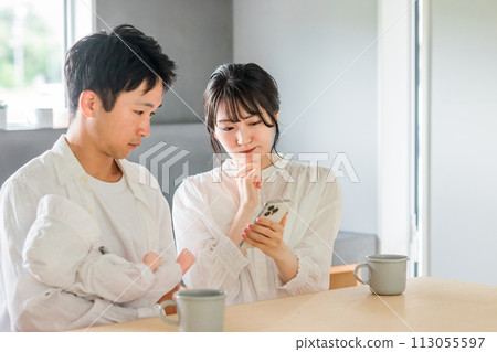 A young Asian couple who is having trouble raising children and looks it up on their smartphone A young Asian couple who is having trouble raising children and looks it up on their smartphone 113055597