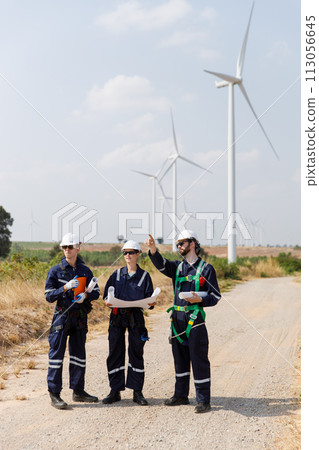 Team engineer wind turbine worker safety uniform survey discuss operational planning windmill field 113056645