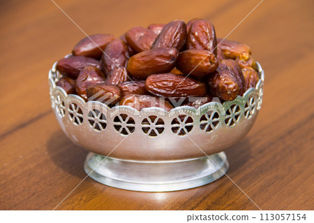 Dates fruit on a silver bowl on wooden table. The Muslim feast of the holy month of Ramadan Kareem 113057154
