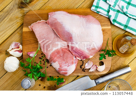Raw slice of Iberian pork secret on wooden cutting board with seasonings 113057448