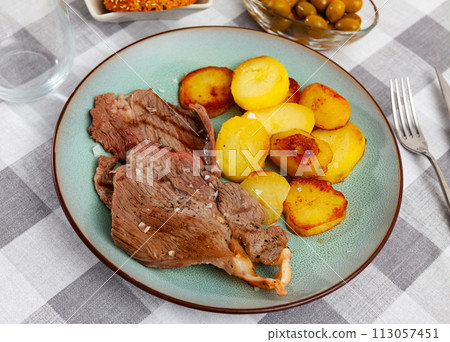 Delicious roasted beef steak with baked potato served with bread and olives Delicious roasted beef steak with baked potato served with bread and olives 113057451