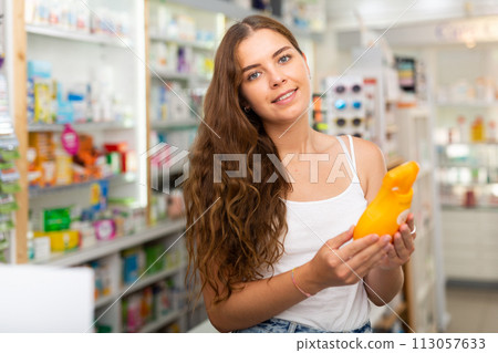 Young woman who came to the pharmacy chooses a hair care remedy Young woman who came to the pharmacy chooses a hair care remedy 113057633