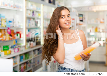 Young woman who came to the pharmacy chooses a hair care remedy Young woman who came to the pharmacy chooses a hair care remedy 113057656