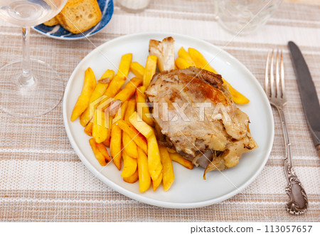 Braised pork knuckle served with garnish of crispy french fries 113057657