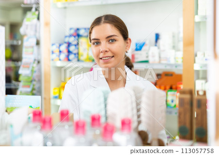 Portrait of a young female pharmacist standing behind the counter of a pharmacy 113057758
