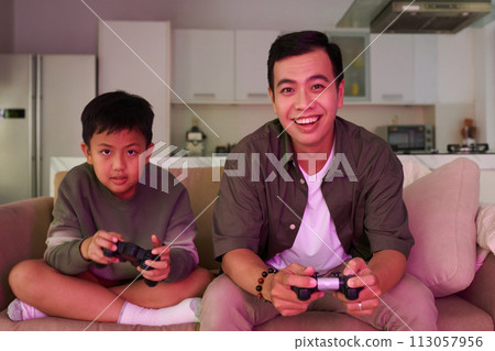 Excited father and son playing videogames at home Excited father and son playing videogames at home 113057956