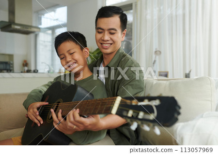 Smiling father teaching son to play chords Smiling father teaching son to play chords 113057969