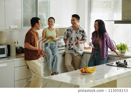 Cheerful people standing in kitchen, having drinks and discussing news Cheerful people standing in kitchen, having drinks and discussing news 113058153