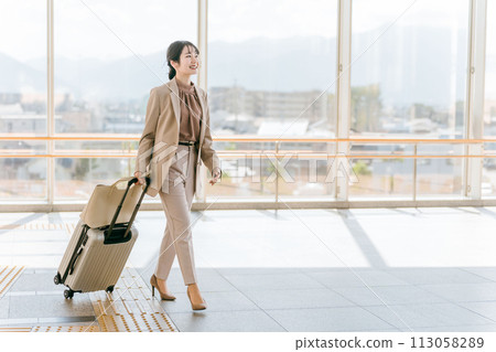 Businesswoman walking with a suitcase at the airport, station, building, public transport facility (overseas business trip, walking) Businesswoman walking with a suitcase at the airport, station, building, public transport facility (overseas business trip, walking) 113058289